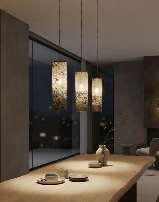 3 suspensions en feuille d'ardoise rustique Swan allumées au dessus d'une table à manger dans un intérieur contemporain, Style wabi-sabi. Atelier Maus