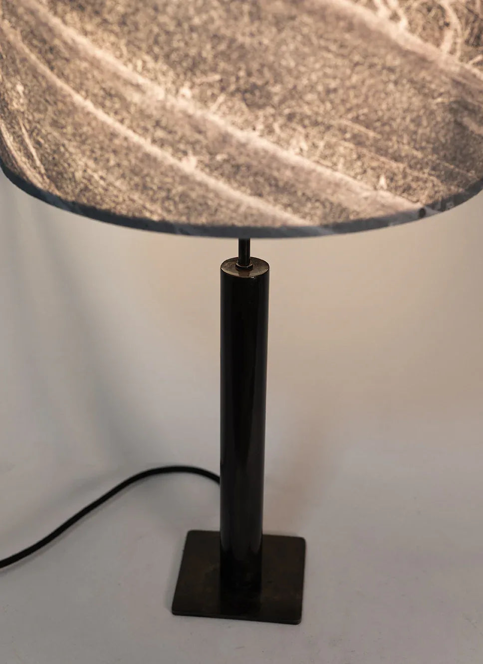Photo en gros plan de la lampe Rosalynd en acier patiné et feuille de marbre allumée | Atelier Maus