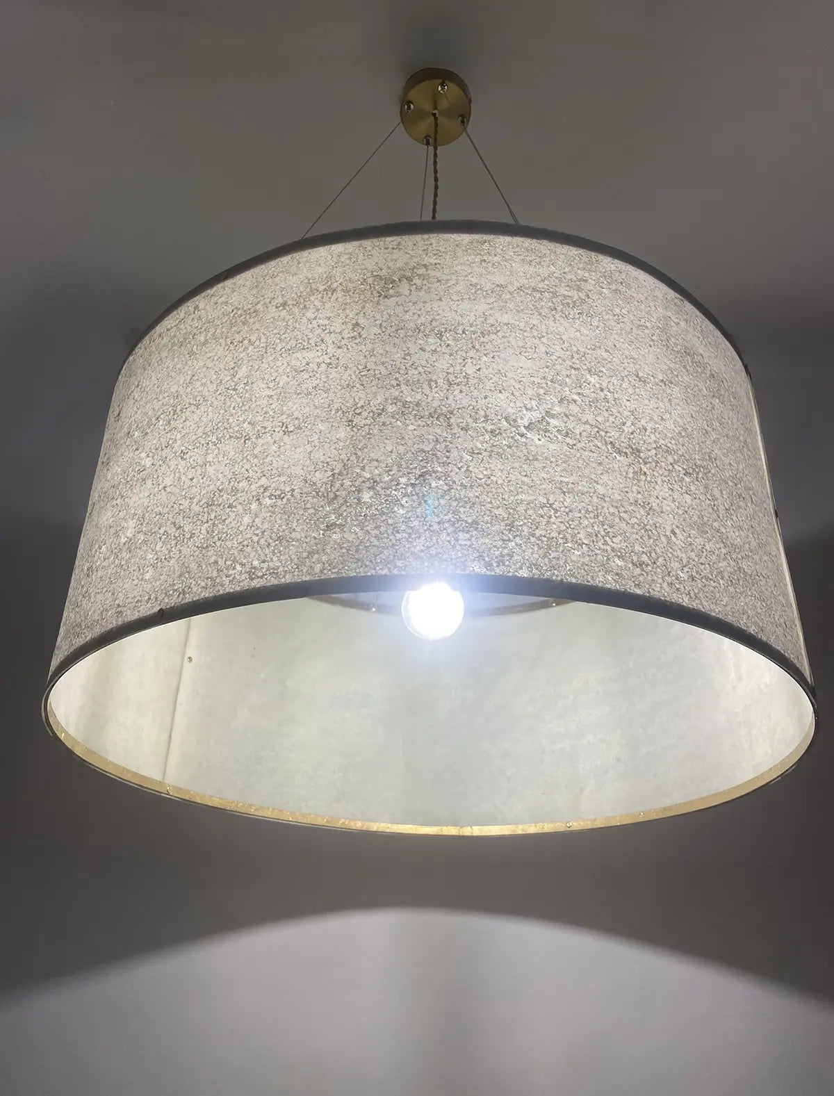 gros plan sur la suspension en feuille de mica vert gris naturelle de 63 cm allumée - Collection Thessalie de l'atelier Maus - Pièce unique de fabrication artisanale française